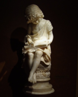 Alabaster sculpture of a child reading a book. The origin of this sculpture is that of Italy from 1880.